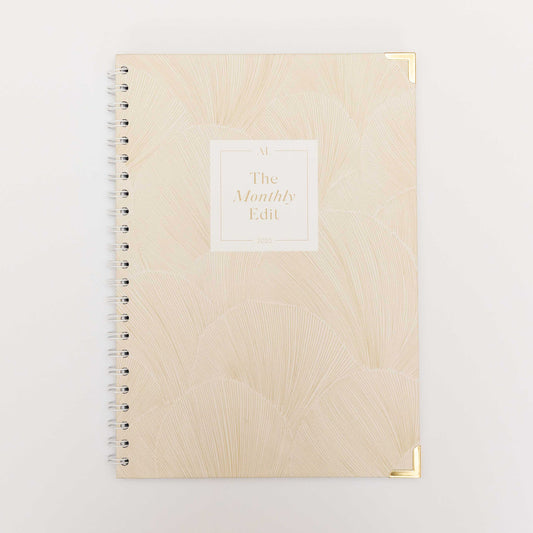 The Monthly Edit - 2025 Planner by Alexa Lily with beige cover, gold corner protectors, and spiral binding